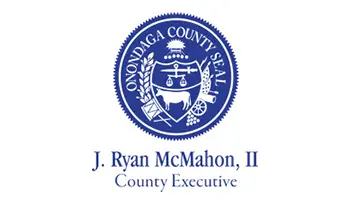 A blue seal with the words j. Ryan mcmahon, ii county executive in it's center